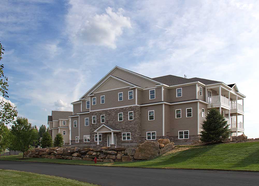 Apartment building exterior next to large boulder retaining wall