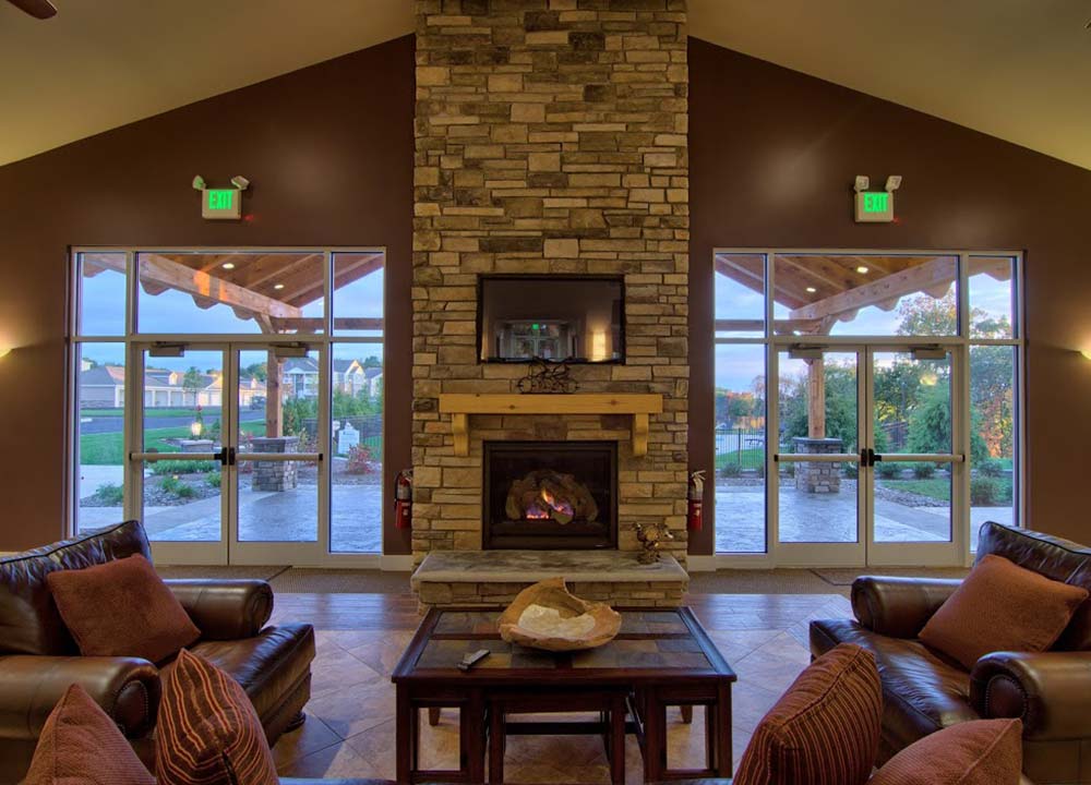 indoor fireplace with large windows and chairs